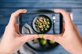 Blogger taking picture of delicious Brussels sprouts with bacon at table. Food photography