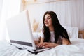 Blogger typing on laptop sitting on bed at home Royalty Free Stock Photo