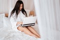 Blogger typing on laptop sitting on bed at home Royalty Free Stock Photo