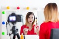 Blogger woman applying cosmetics at camera