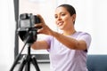 Female video blogger adjusting camera at home