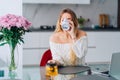 Blond attractive woman kitchen drinking herb citron tea teapot, laptop. Flowers Royalty Free Stock Photo