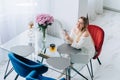 Blond attractive woman kitchen drinking herb citron tea teapot, laptop. Flowers Royalty Free Stock Photo