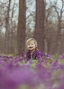 Blond baby in a colored dress lies in a forest glade in flowers