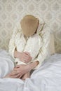 Blond bald woman sitting on bed