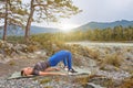 Blond beautiful girl is making a warm-up lying on the stone ground in the pose of the bridge, resting his palms and shoulder Royalty Free Stock Photo