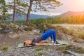 Blond beautiful girl is making a warm-up lying on the stone ground in the pose of the bridge, resting his palms and shoulder Royalty Free Stock Photo