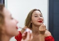 Blond beautiful woman aplying a red lipstick and looking at the mirror Royalty Free Stock Photo