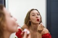 Blond beautiful woman aplying a red lipstick and looking at the mirror Royalty Free Stock Photo