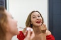 Blond beautiful woman aplying a red lipstick and looking at the mirror Royalty Free Stock Photo