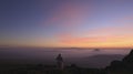 A blond big woman looks at the cloudy horizon at sunrise