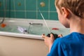 Blond boy with British flag on blue Tshirt playing with radio controled boat in bathroom Royalty Free Stock Photo