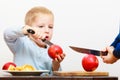 Blond boy child kid preschooler with kitchen knife cutting fruit apple Royalty Free Stock Photo