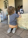 Blond boy with curly hair like an angel kneeling on the ground playing with his gray truck in a simple house in the interior of Royalty Free Stock Photo