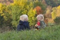 Blond boy and girl sit on grass and eat apples. Little siblings resting in nature. Children on picnic on autumn day Royalty Free Stock Photo