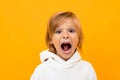 Blond boy grimaces on an orange studio background close-up Royalty Free Stock Photo