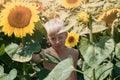 Blond boy hiding in a sunflower field. Holidays in the countryside. Harvest