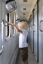 Blond boy with interest looks in the window of the train. Traveling with children Royalty Free Stock Photo