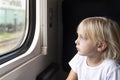 Blond boy looks thoughtfully out the train window. Rail travel