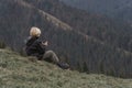 Blond boy in mountains resting on hillside with cup of tea. Hiking with child. Active recreation or vacation