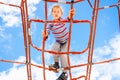 Blond boy perched on a web rope-ladder structure in a children`s playground for fun climbing Royalty Free Stock Photo