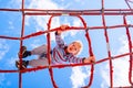 Blond boy perched on a web rope-ladder structure in a children`s playground for fun climbing Royalty Free Stock Photo