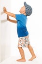 Blond boy pushing he wall white bacground Royalty Free Stock Photo