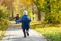 Blond boy runs to meet her mother. Autumn park. Back view