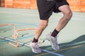 Blond boy in sportswear jumps over red obstacles to improve lower body dynamics. Plyometric training in an outdoor environment.