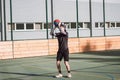 Blond boy in sportswear practices shooting a basketball from behind the three-point line. Outdoor basketball court. Preparing for