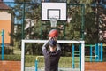 Blond boy in sportswear practices shooting a basketball from behind the three-point line. Outdoor basketball court. Preparing for