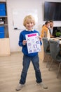 Blond boy standing and holding paper with physics drawings Royalty Free Stock Photo