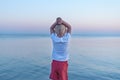 Blond boy stands on sea background and sunset. Calm and relax concept. Back view Royalty Free Stock Photo