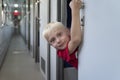 Blond boy in train carriage looks out of compartment. Traveling with children by train Royalty Free Stock Photo
