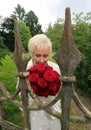 Happy bride breathes the scent of red roses behind the old castle fence