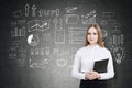 Blond businesswoman with a notebook near a chalkboard with a sta Royalty Free Stock Photo