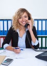 Blond businesswoman at office at phone laughing at camera Royalty Free Stock Photo