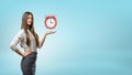 A blond businesswoman stands and holds one hand palm up with red retro alarm clock hovering above it. Royalty Free Stock Photo