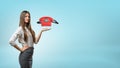 A blond businesswoman stands and holds one hand palm up with a red retro phone hovering above it. Royalty Free Stock Photo