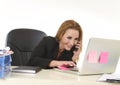 Blond businesswoman working at office laptop computer desk talking on mobile phone smiling Royalty Free Stock Photo