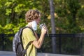 A blond caucasian man wearing face mask due to COVID-19 is temporarily removing part of his mask to take a sip from the cold drink Royalty Free Stock Photo