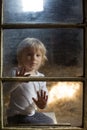 Blond child behind the window, looking outside