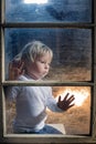 Blond child behind the window, looking outside