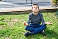 Blond child doing yoga exersice sitting on grass at park