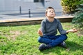 Blond child doing yoga exersice sitting on grass at park