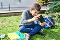 Blond child playing video game sitting on grass at park Royalty Free Stock Photo