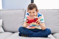 Blond child playing video game sitting on sofa at home Royalty Free Stock Photo