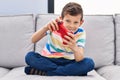 Blond child playing video game sitting on sofa at home Royalty Free Stock Photo