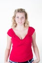 blond european woman standing with hands in pockets, wearing red shirt