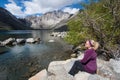 Blond female sits alone by Convict Lake in the springtime, located off of US-395, near Mammoth Lakes California in the eastern